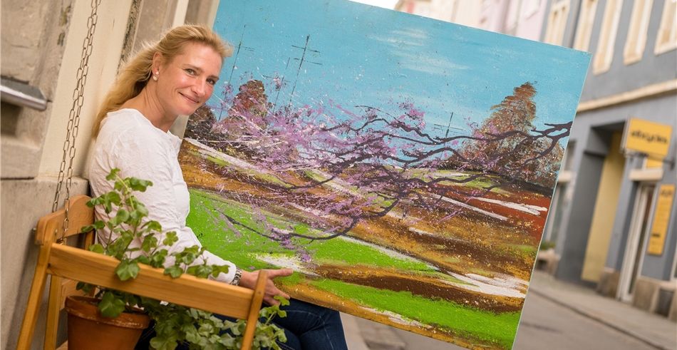 Ulrike Reckziegel zeigt ein Bild von der Malerin Ramona Hellmann